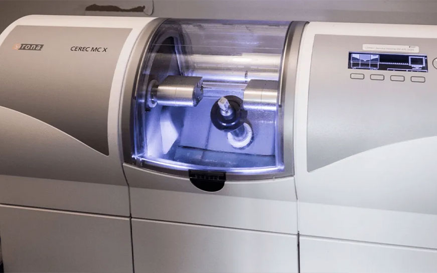 This is a photograph of an industrial 3D printer with its door open, revealing its interior and print bed.