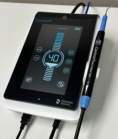 The image shows a dental device with an attached monitor displaying various data points such as temperature and pressure, accompanied by a pen-like object which appears to be a stylus for interacting with the screen.