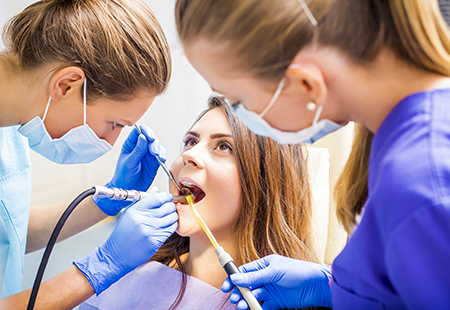 An image depicting dental care professionals performing oral examinations on patients using dental tools.