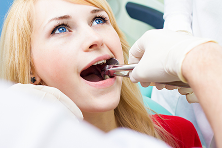 The image shows a dental professional assisting a patient during a dental procedure.