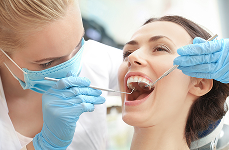 The image shows a dental hygienist performing oral care on a patient, with the patient smiling and wearing blue gloves.